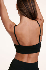 Back view of Linni wearing the Cloud Cotton Triangle Bralette in Black, featuring thin adjustable straps and a smooth longline band.
