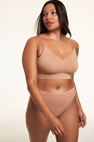 In a softly lit studio, Alana wears the Cloud Cotton Triangle Bralette and Cloud Cotton French Cut Brief in Dune. The bralette features a deep V neckline, thin adjustable straps, and soft cotton modal fabric, paired with a high-rise French cut brief with a high leg silhouette and moderate coverage.