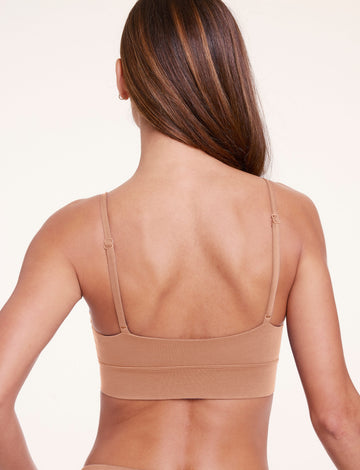 Back view of Linni wearing the Cloud Cotton Triangle Bralette in Dune, highlighting the adjustable straps, smooth back band, and soft cotton modal fabric.