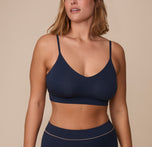 Sonnie wearing the Cloud Cotton Triangle Bralette in Midnight. The low v-neck neckline and thin straps are emphasized. sizing: Sonnie wears size XL