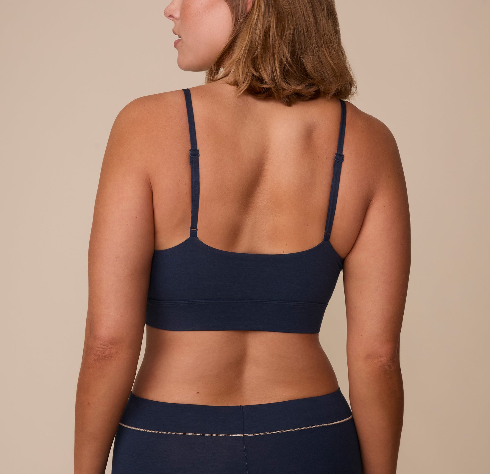 Sonnie wearing the Cloud Cotton Triangle Bralette in Midnight. The thin adjustable straps and wide smooth back panel are emphasized. 