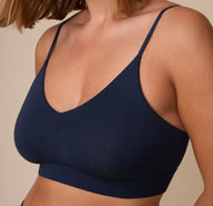 Up close view of Sonnie wearing the Cloud Cotton Triangle Bralette in Midnight. The low v-neck neckline and deep blue, cotton-modal fabric are emphasized. 