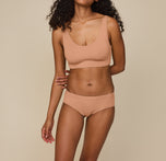 Zoe standing with hands at her sides, wearing the Cloud Cotton Scoop Bralette and Cloud Cotton Hiphugger in Dune. The hiphugger offers a soft, mid-rise fit with full back coverage, made from breathable cotton-modal fabric. sizing: Zoe wears size XS