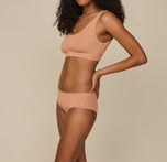 Side view of Zoe wearing the Cloud Cotton Scoop Bralette and Cloud Cotton Hiphugger in Dune, emphasizing the hiphugger’s comfortable mid-rise design and elastic-free waistband for a smooth, no-dig fit.