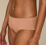 Close-up of Zoe wearing the Cloud Cotton Hiphugger in Dune, focusing on the elastic-free waistband that lies flat under clothing and the soft, breathable fabric made of a cotton-modal blend.