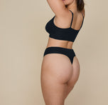Close-up side view of Summerlyn wearing the Cloud Cotton Highwaist Thong in Black, highlighting the high-rise waistband and minimal coverage design of the thong.