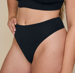 Close-up side view of Summerlyn in the Cloud Cotton Triangle Bralette and Cloud Cotton Highwaist Thong in Black, highlighting the thong’s the high-rise waistband.