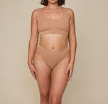 Front view of Kate wearing the Cloud Cotton Highwaist Thong in Dune, emphasizing the soft, highwaisted design.