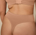 Close-up of Kate wearing the Cloud Cotton Highwaist Thong in Dune, highlighting the soft, breathable fabric and minimal back coverage of the thong.