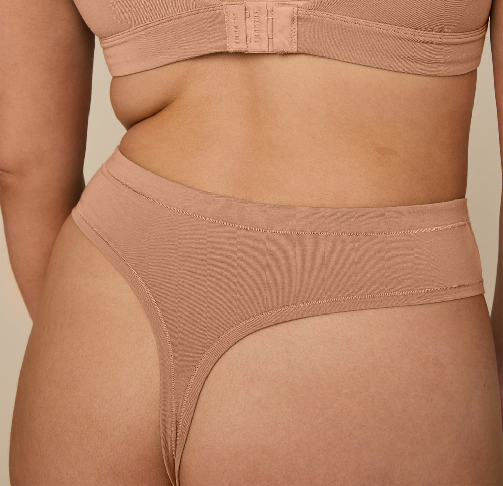 Close-up of Kate wearing the Cloud Cotton Highwaist Thong in Dune, highlighting the soft, breathable fabric and minimal back coverage of the thong.