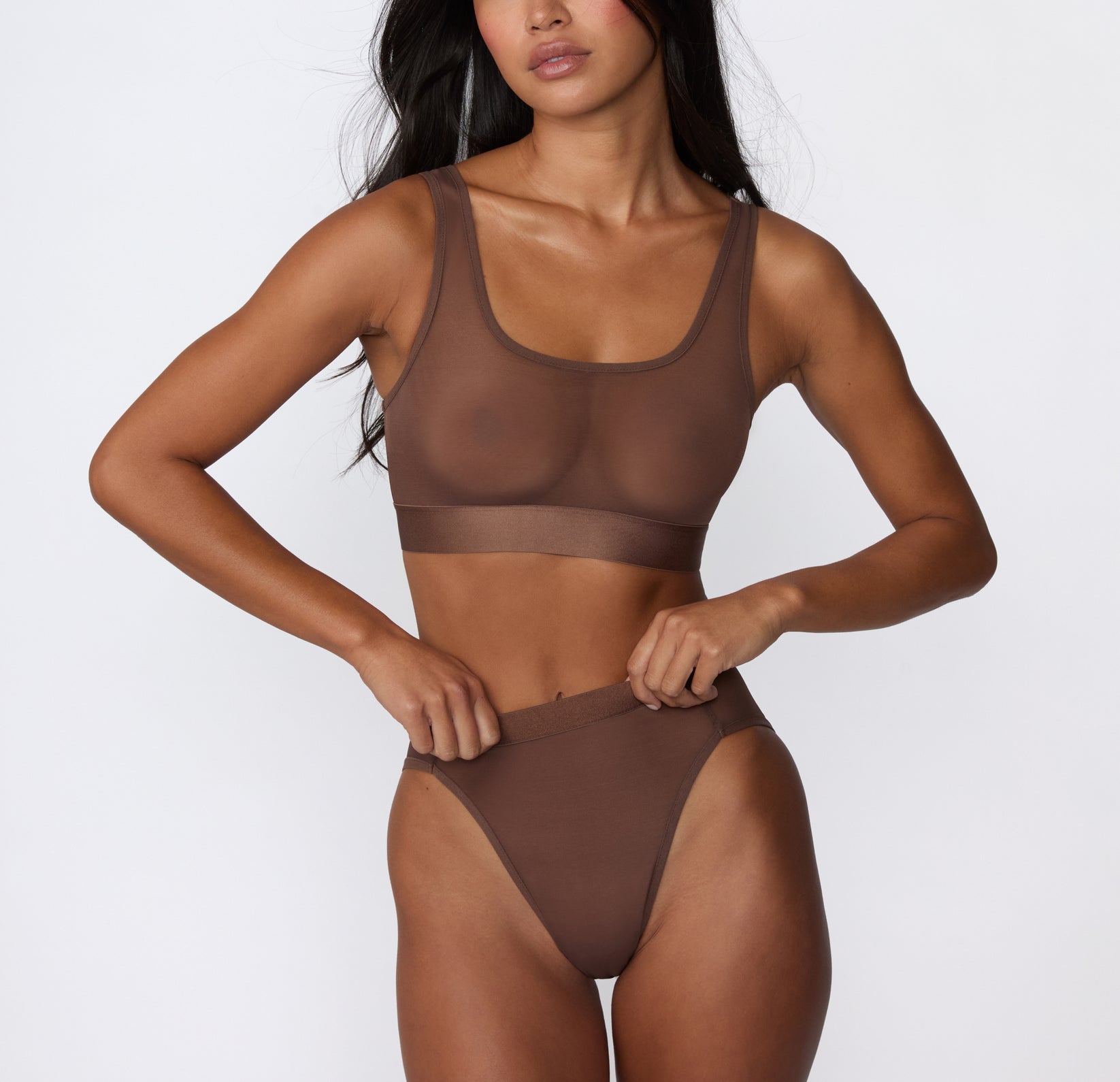 On a white studio backdrop, Amber wears the ComfortMesh™ Highwaist in Cashmere with the matching bralette, shown in a front-facing view highlighting the sheer mesh fabric and smooth, supportive waistband.