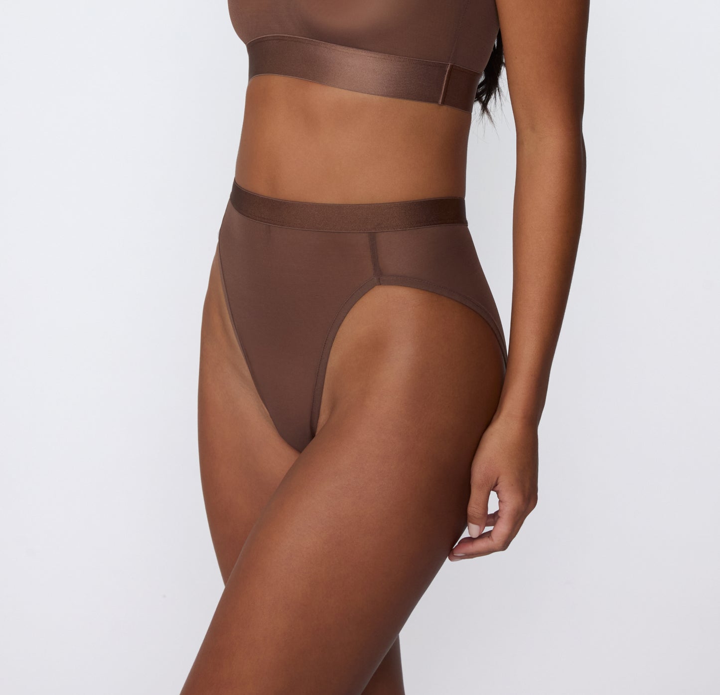 On a white studio backdrop, a three-quarter side view shows Amber wearing the ComfortMesh™ Highwaist in Cashmere, highlighting the sheer mesh fabric, high-rise silhouette, and smooth waistband.