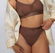 On a white studio backdrop, a three-quarter front view shows Amber wearing the ComfortMesh™ Highwaist in Cashmere with the matching bralette, highlighting the sheer mesh fabric and high-rise silhouette.