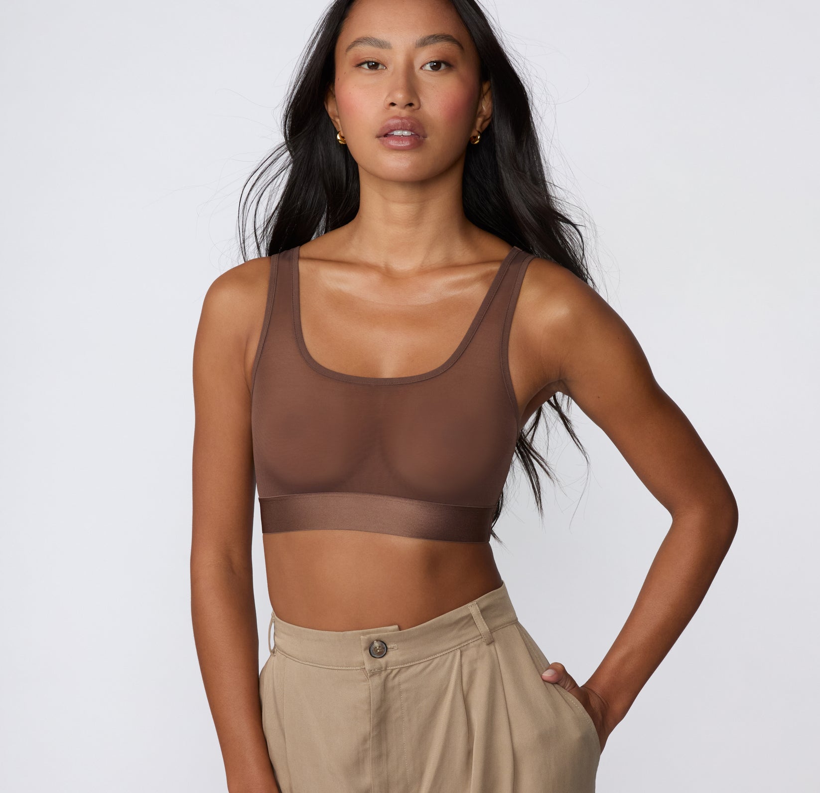 On a white studio backdrop, Amber wears the ComfortMesh™ Scoop Bralette in Cashmere, shown in a front-facing view highlighting the sheer mesh fabric, scoop neckline, and wide supportive band.