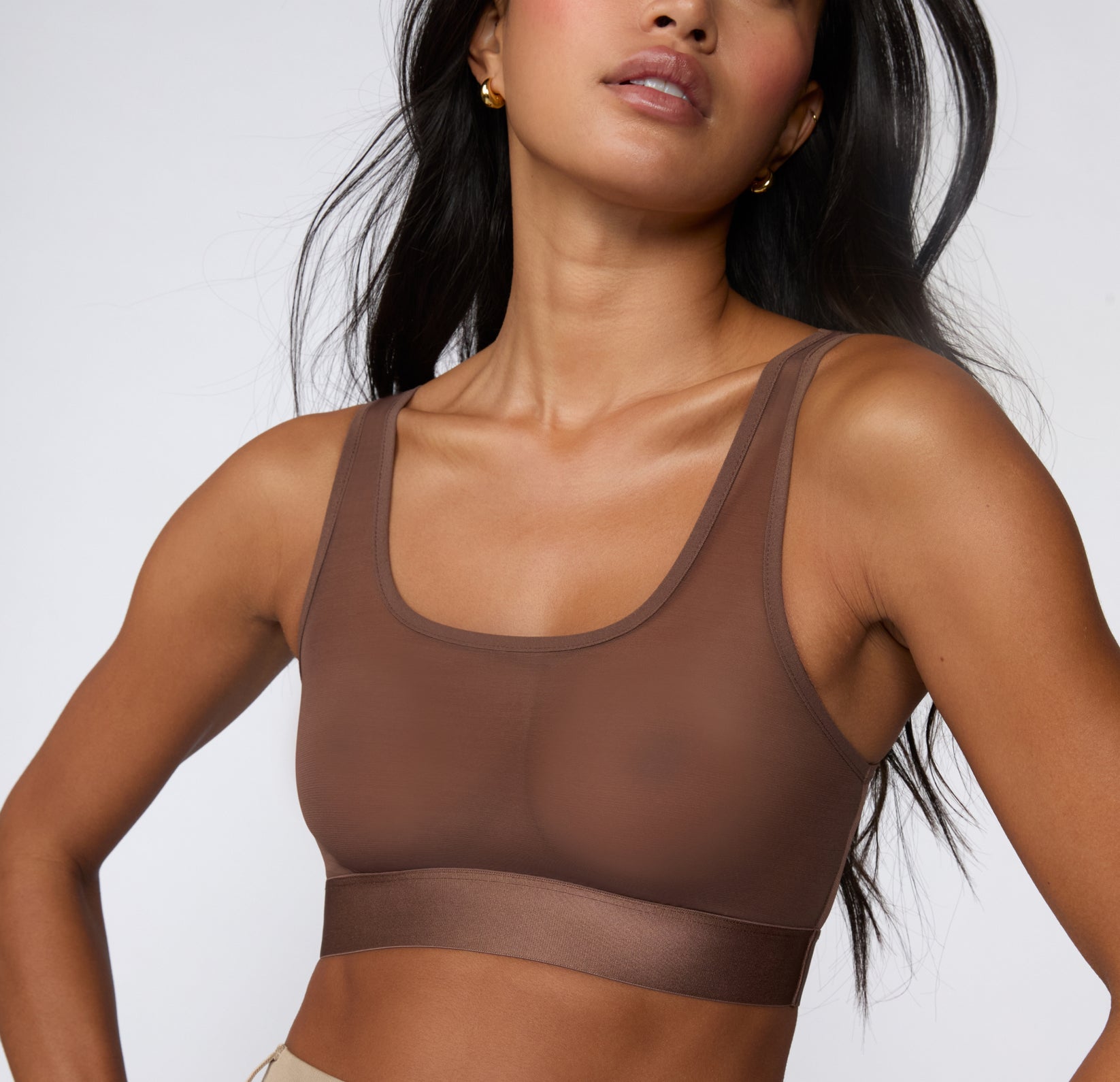 On a white studio backdrop, a three-quarter view shows Amber wearing the ComfortMesh™ Scoop Bralette in Cashmere, highlighting the sheer mesh fabric, wide straps, and supportive band.