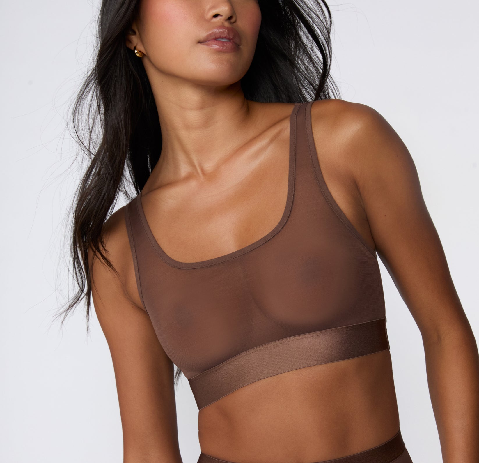 On a white studio backdrop, a close-up angled view shows Amber wearing the ComfortMesh™ Scoop Bralette in Cashmere, focusing on the scoop neckline, sheer mesh cups, and smooth microfiber band.
