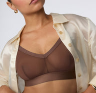 On a clean studio backdrop, India wears the ComfortMesh™ Triangle Bralette in Cashmere, shown in a close-up view highlighting the sheer mesh fabric, deep V neckline, and wide supportive band. sizing: India wears size Large