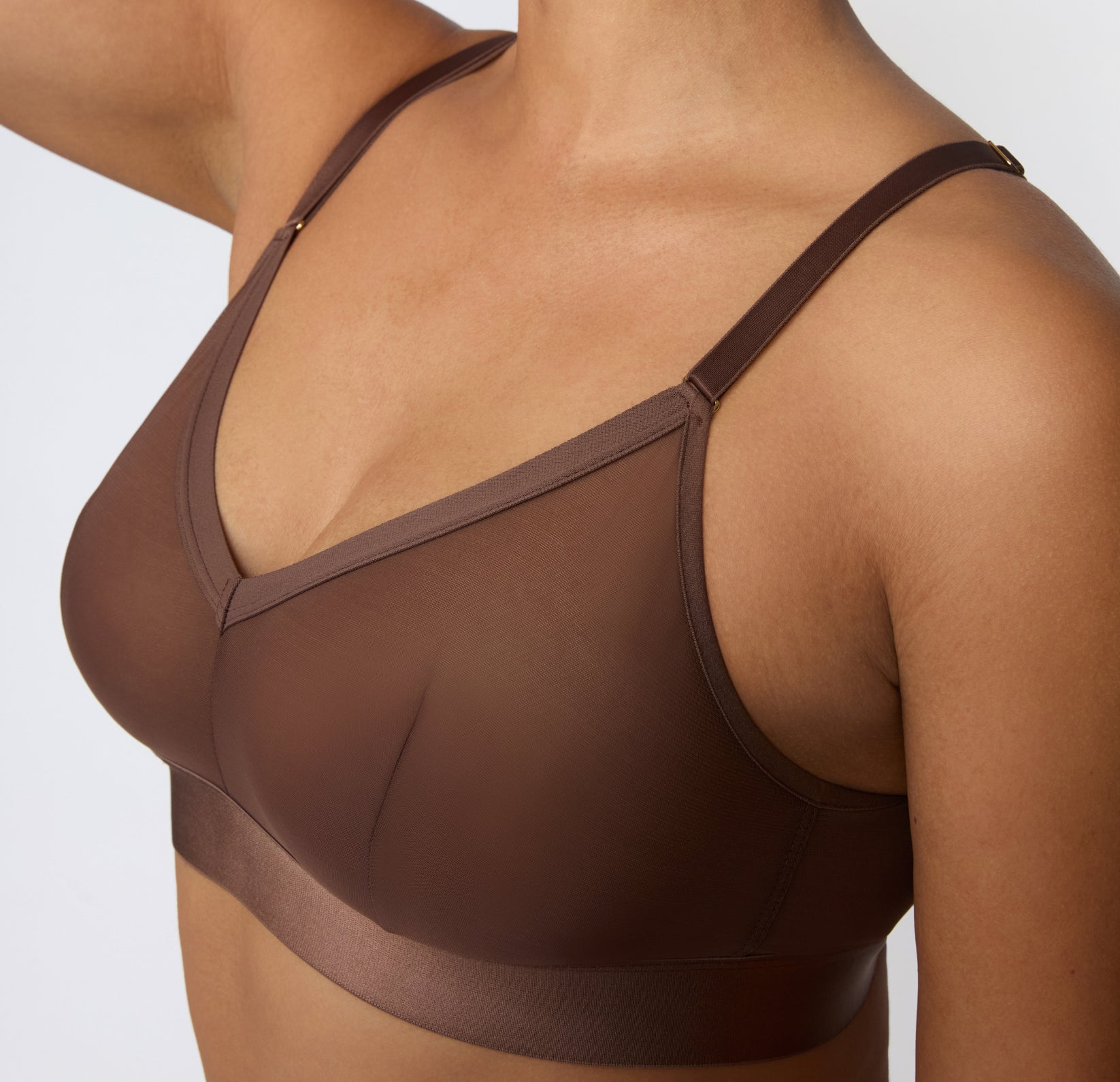 On a white studio backdrop, a close-up side view shows India wearing the ComfortMesh™ Triangle Bralette in Cashmere, highlighting the sheer mesh cups, adjustable straps, and smooth microfiber band.