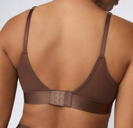 On a white studio backdrop, a back view shows India wearing the ComfortMesh™ Triangle Bralette in Cashmere, featuring the adjustable straps, hook-and-eye closure, and wide supportive band.