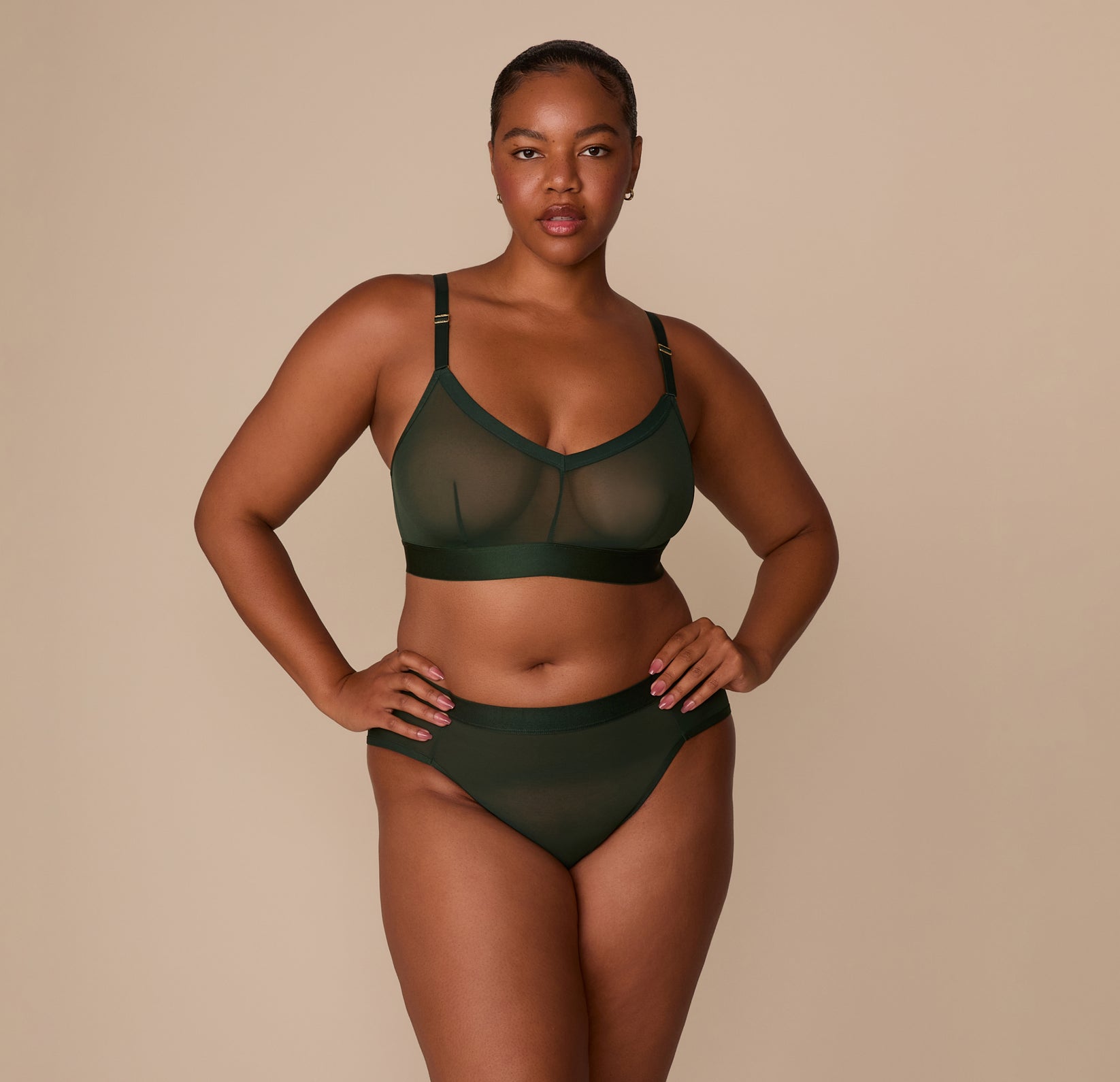 Zarria stands with hands on hips wearing the ComfortMesh™ Highwaist Brief and matching Triangle Bralette in Sequoia. The full set showcases the coordinated sheer design.