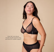 Emersyn poses, twisting slightly so that the ComfortMesh Plunge Bra in Black's double layered sling is visible. A tagline reads "Sizes 36C and above include double layered sling and band for added support". 