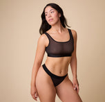 Full body shot of Emersyn wearing the ComfortMesh™ Thong in Black that highlights the wide, comfortable band and seamless design. 