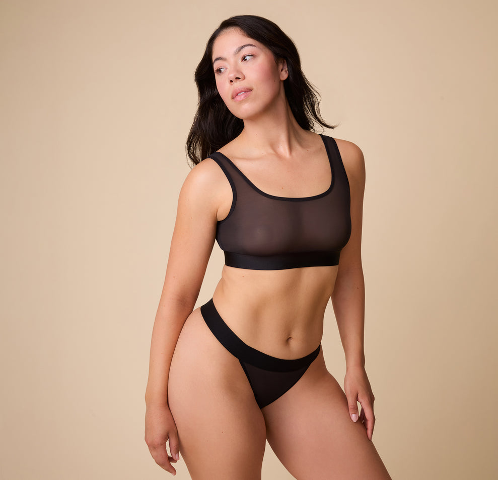 Full body shot of Emersyn wearing the ComfortMesh™ Thong in Black that highlights the wide, comfortable band and seamless design. 