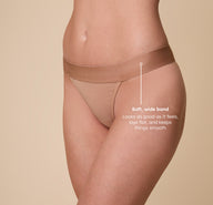 A close-up shot of Gracie wearing the ComfortMesh™ Thong in Taupe. The image features a tagline reading, “Soft, wide band – Looks as good as it feels, lays flat, and keeps things smooth,” emphasizing the thong’s comfort and practicality.