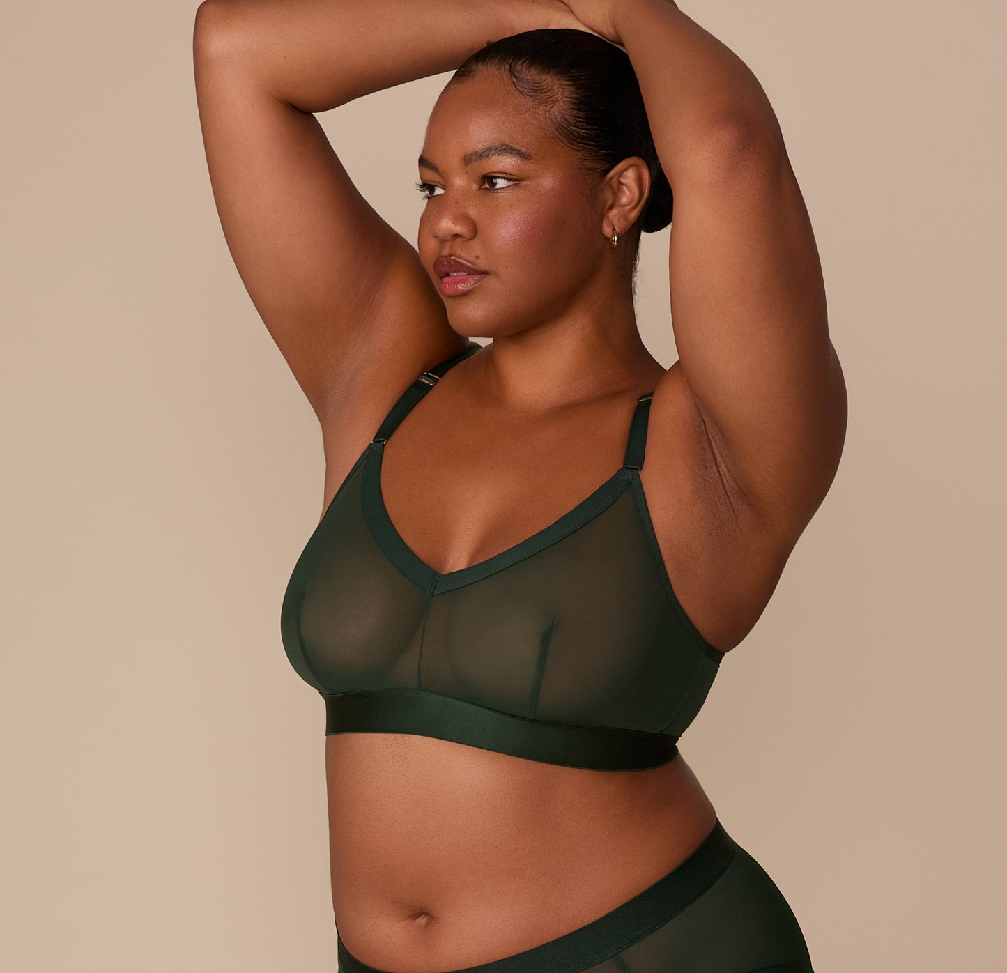 Side view of Zarria with arms raised, wearing the ComfortMesh™ Triangle Bralette in Sequoia. The adjustable straps and soft mesh are visible across the bust and shoulders.