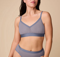 Emersyn wearing the ComfortMesh™ Triangle Bralette in Steel. The front view shows the deep V neckline, wide elastic band, and breathable mesh cups designed for wire-free support. sizing: Emersyn wears size Medium