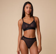 Full view of Ally modeling the ComfortMesh Triangle Bralette in Black with matching high-waist bottoms, showcasing the modern and chic silhouette.