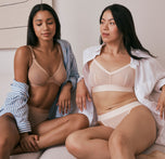 Ally and Emersyn sitting on a couch. Ally is wearing the ComfortMesh™ Plunge Bra in Taupe, while Anna is styled in the  ComfortMesh™ Triangle Bralette in Pearl. Both are dressed in an elegant, casual aesthetic.
