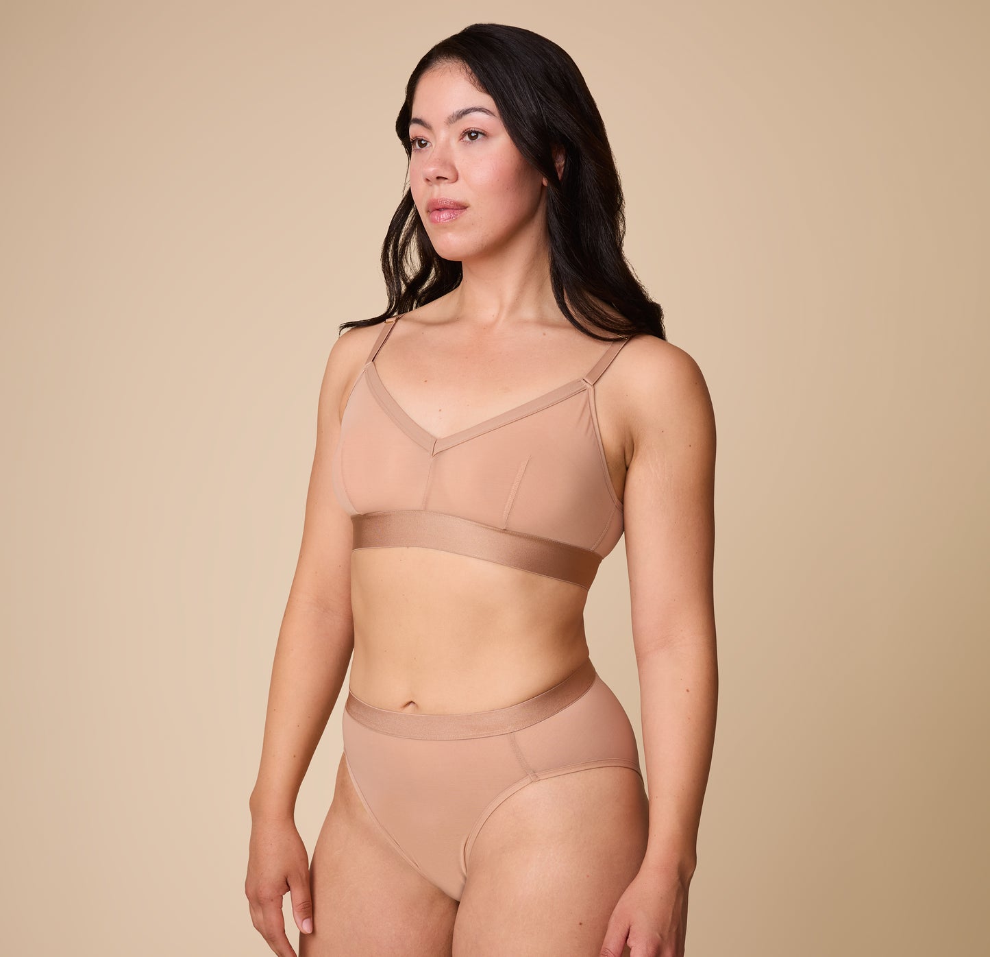 Emersyn standing in a side pose, wearing the ComfortMesh™ Triangle Bralette in Taupe, emphasizing its comfortable fit and stretchy band.