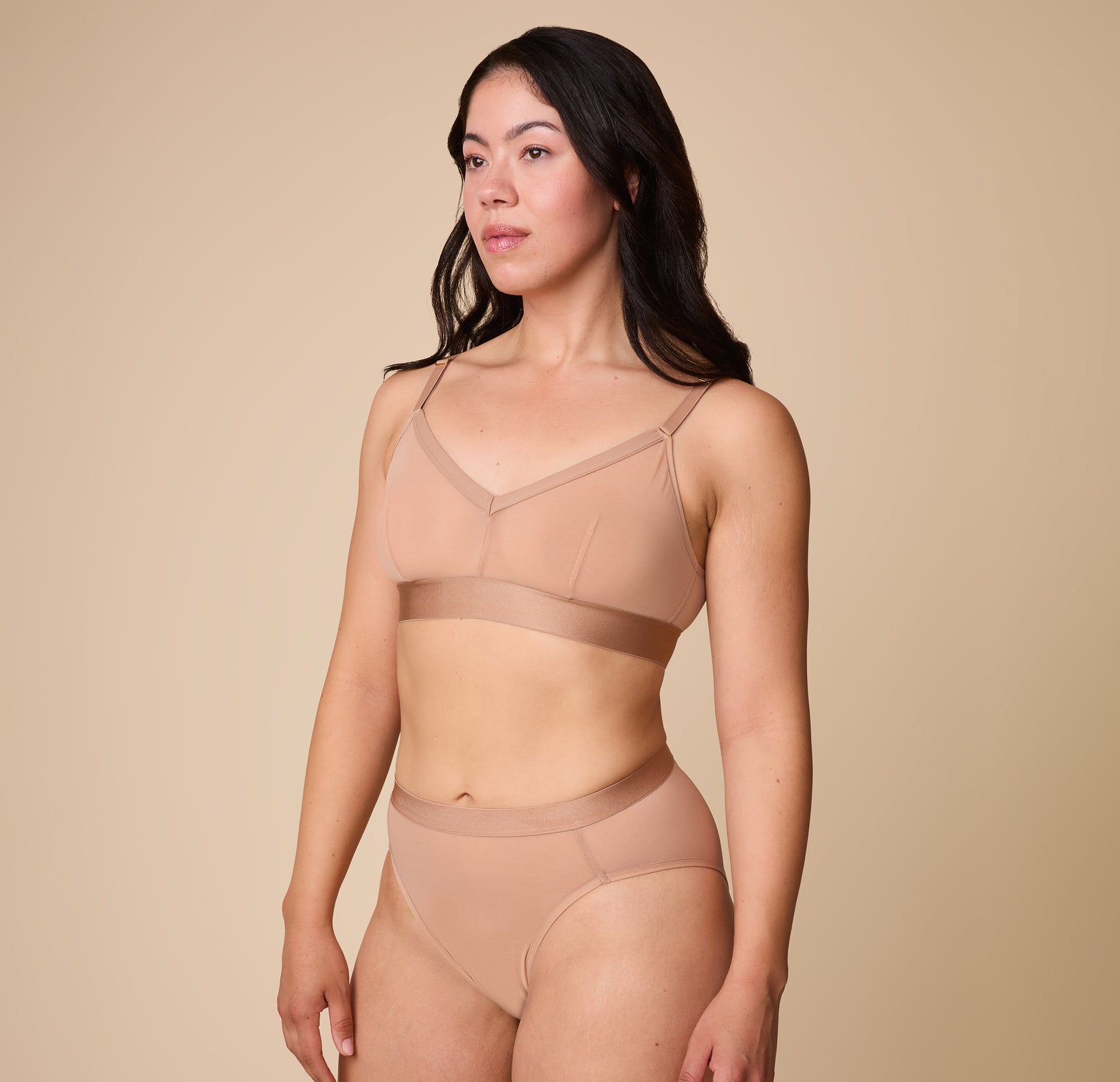 Emersyn standing in a side pose, wearing the ComfortMesh™ Triangle Bralette in Taupe, emphasizing its comfortable fit and stretchy band.