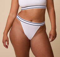 Front view of India wearing the Cloud Cotton Retro French Cut Bikini in White. The image highlights the high-leg cut and soft, stretchy waistband with black and white stripes. sizing: India wears size Large