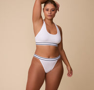 Full-body view of India in the Cloud Cotton Retro French Cut Bikini in White, styled with the matching Racerback Bralette. She poses confidently against a neutral background.