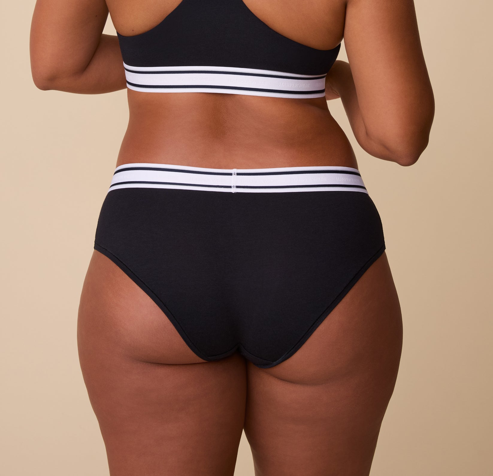 Back view of the Cloud Cotton Retro Hiphugger in Black. India showcases the full-coverage back with a smooth fit, emphasizing the soft fabric and supportive waistband.