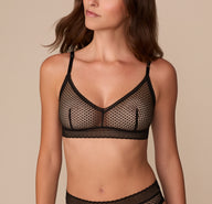 Front view of Alexis wearing the Dot Lace Triangle Bralette in Black. The bralette features a soft V-neckline, all-over geometric lace, and a supportive wireless band. sizing: Alexis wears size Small