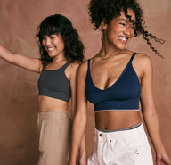 Two models standing next to each other wearing the Lounge Rib Scoop Bralette and the Lounge Rib Triangle Bralette.