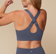 Megan showing the back of the Flex Convertible Sports Bra in Slate, with the straps adjusted to cross in the back.