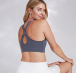 Megan sitting in the Flex Convertible Sports Bra in Slate, showcasing the convertible back strap detail, paired with a white skirt.