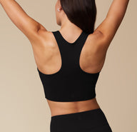 Back view of Anna wearing the Flex Racerback Sport Tank in Black. The Racerback feature and wide comfortable straps are emphasized.