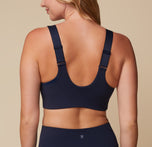 Back view of Megan wearing the Flex Convertible Sports Bra in Ink. The thick convertible straps and wide, comfortable band are emphasized. sizing: Megan wears size Medium