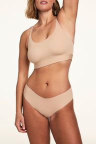 On a light studio backdrop, Sonnie wears the Invisible No-Show Low Rise Thong in Beige with a matching wireless bralette. The low-rise thong features elastic-free edges and a smooth no-show silhouette.