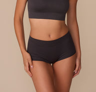 Alexis wearing the Lounge Rib Boyshort in Charcoal, shown from the front. The mid-rise boyshort features a wide, seamless waistband and soft ribbed texture, offering a smooth, stretchy fit. sizing: Alexis wears size Small