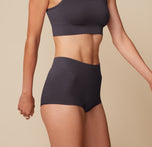Side view of Anna wearing the Lounge Rib Scoop Bralette and Boyshort in Charcoal. The matching set emphasizes the comfort and every day wearability of the products.