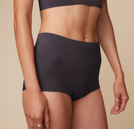 Close up view of Anna wearing the Lounge Rib Boyshort in Charcoal. The wide comfortable waistband and ribbed material are emphasized.