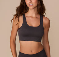 Alexis wearing the Lounge Rib Scoop Bralette in Charcoal, shown from the front, highlighting the wide scoop neckline, supportive ribbed fabric, and seamless construction for a smooth, comfortable fit. sizing: Alexis wears size Small