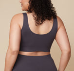 Bianca is turned to the side, showing the back of the Lounge Rib Scoop Bralette and Lounge Rib Boyshort in Charcoal. The seamless design offers full comfort and support.