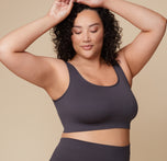 Bianca raises her arms, showcasing the side profile of the Lounge Rib Scoop Bralette and Lounge Rib Boyshort in Charcoal.